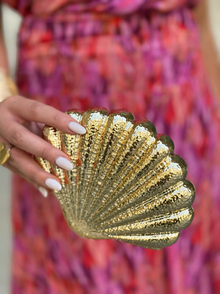 Bolso rígido en metal dorado con diseño de concha escultórica elegante