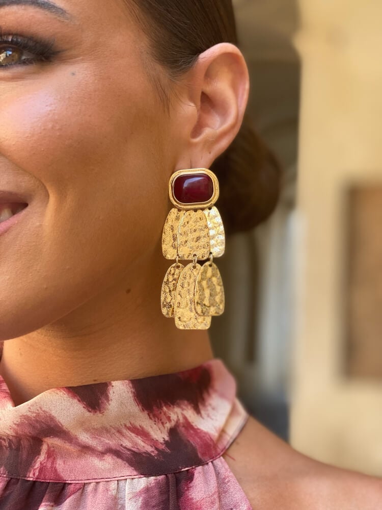 Pendientes en metal dorado con una piedra en tono vino